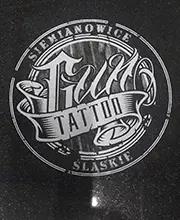 Logotyp studia tatuażu wygrawerowany na nagrobku