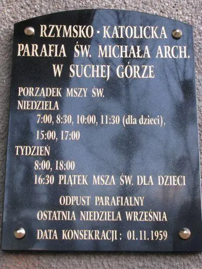 Tablica na kościele św. Michała Archanioła w Suchej Górze prezentująca porządek mszy świętych. Litery złocone.